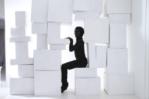 Ilustračný obrázok k článku - Osoba v čiernom pózuje medzi bielymi škatuľami.